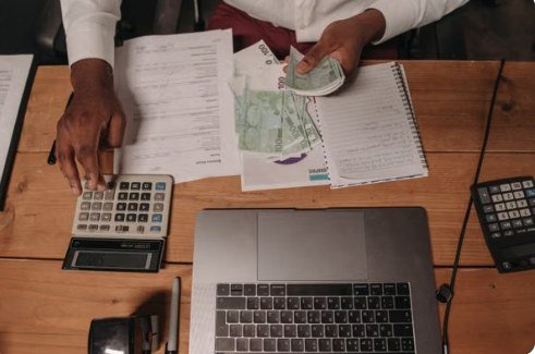 Counting cash beside a laptop and calculator