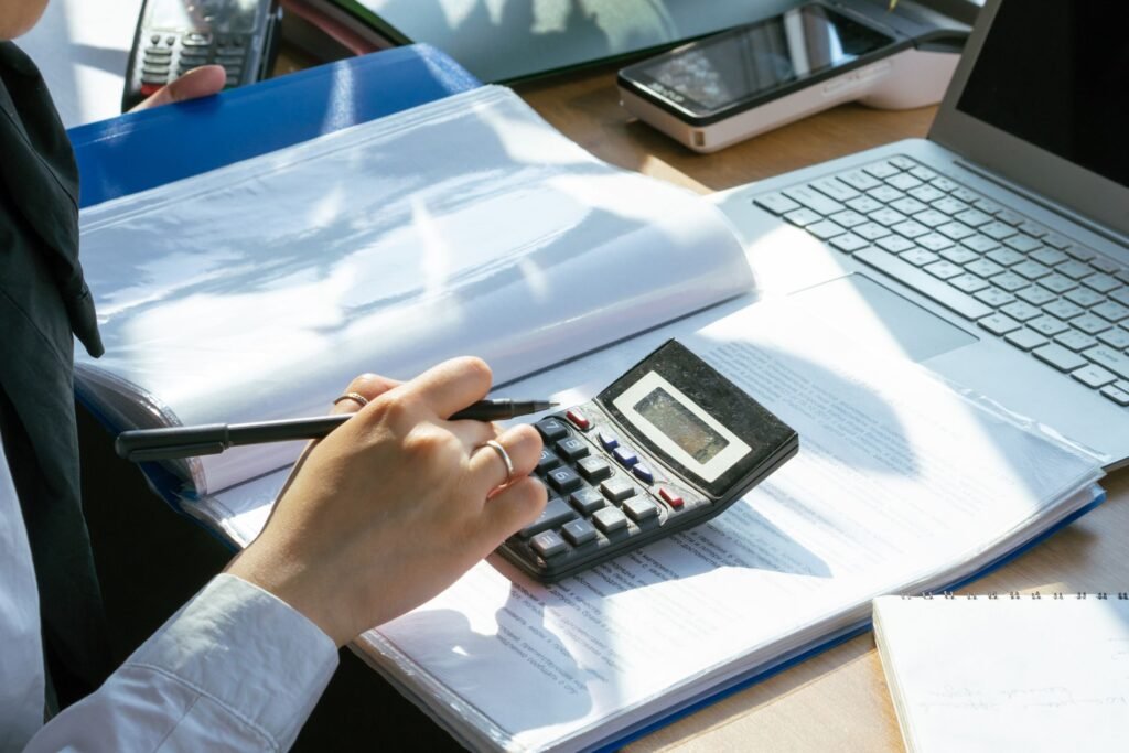 Bookkeeper reconciling paperwork beside a laptop