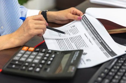 Reviewing a printed financial report with a calculator