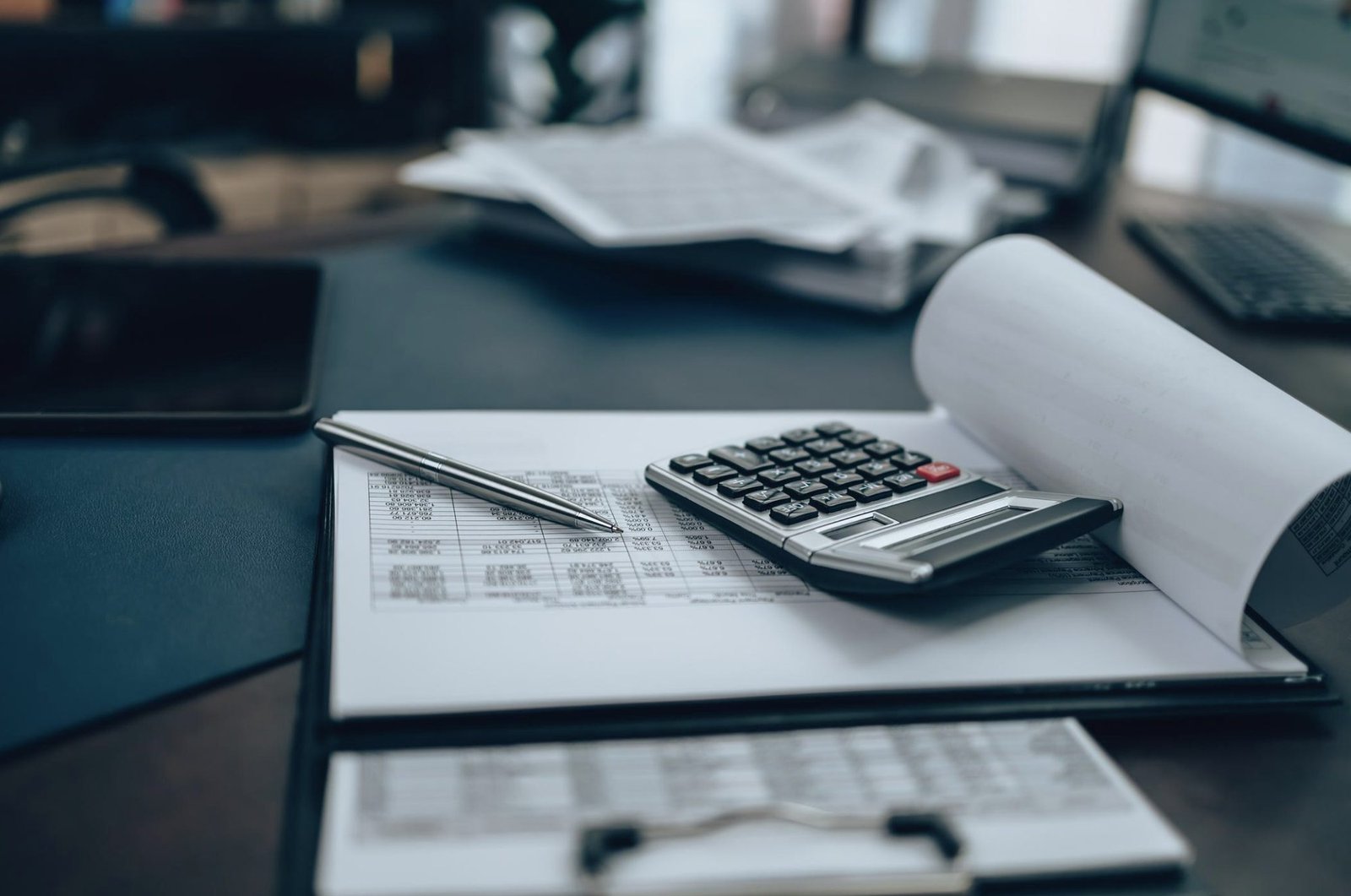 Spreadsheet on a clipboard with a calculator and pen